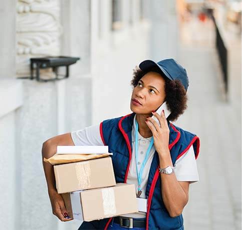 Delivery worker carrying packages while speaking on the phone
